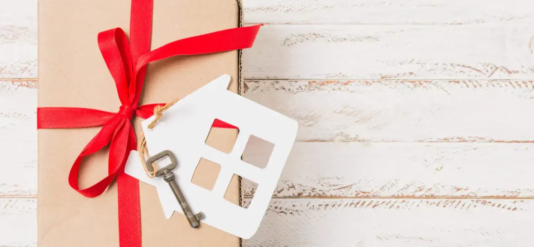 high-angle-view-gift-box-tied-with-red-ribbon-house-key-wooden-table