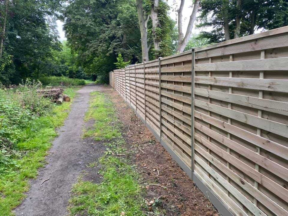New wooden garden fence with duraposts along a woodland path.