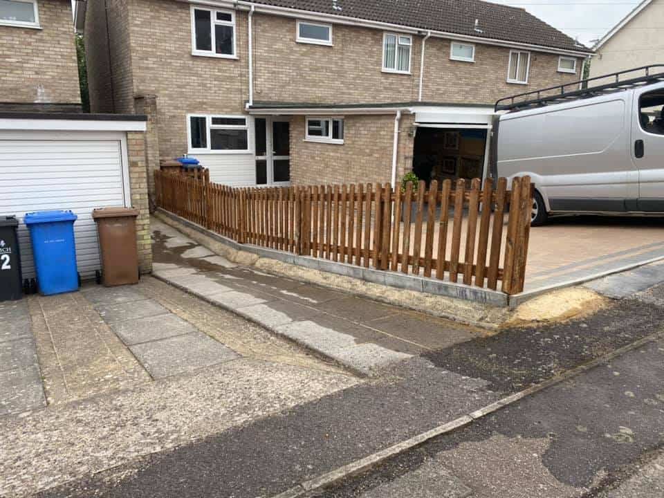 New wooden picket fence installed in front of house for garden boundary.