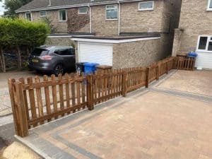 Wooden picket fence installed in a residential driveway area.