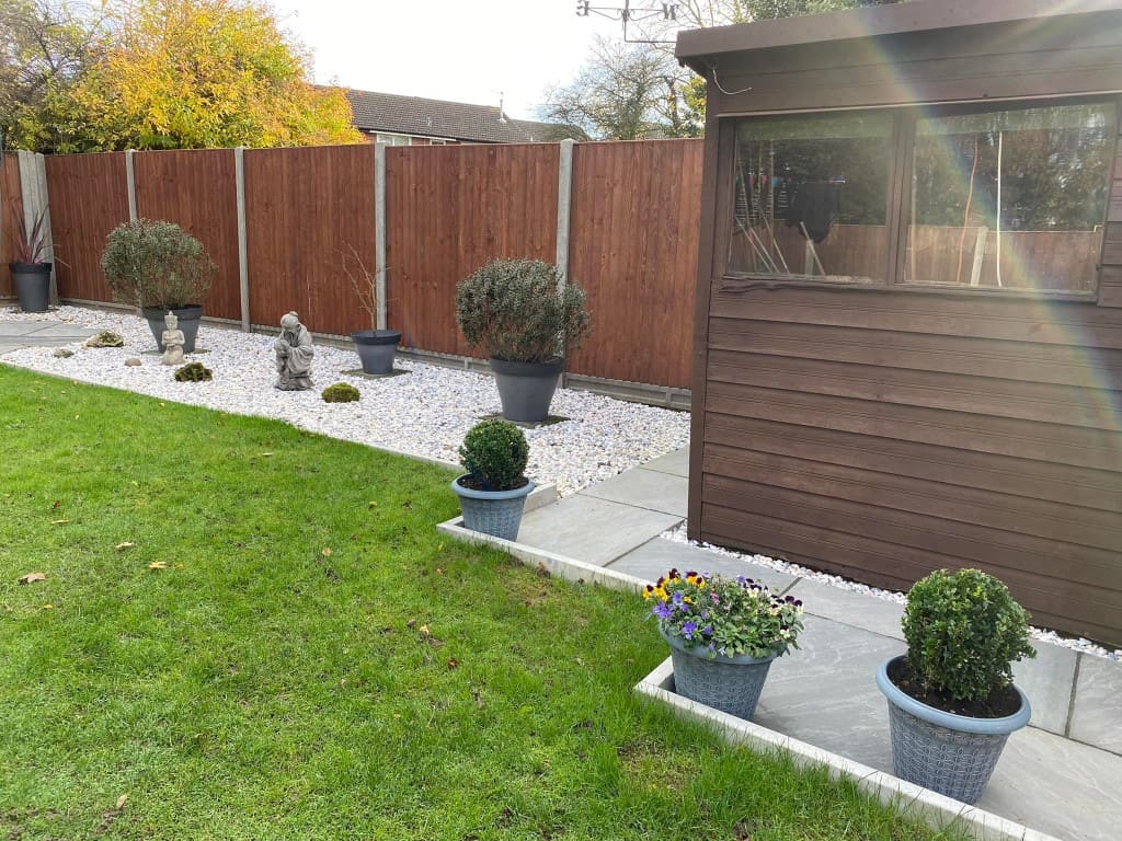 Well-maintained garden with potted plants, gravel, and wooden fence.