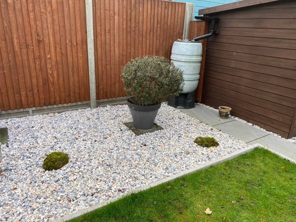 Garden with gravel, potted shrub, and wooden fence for privacy.