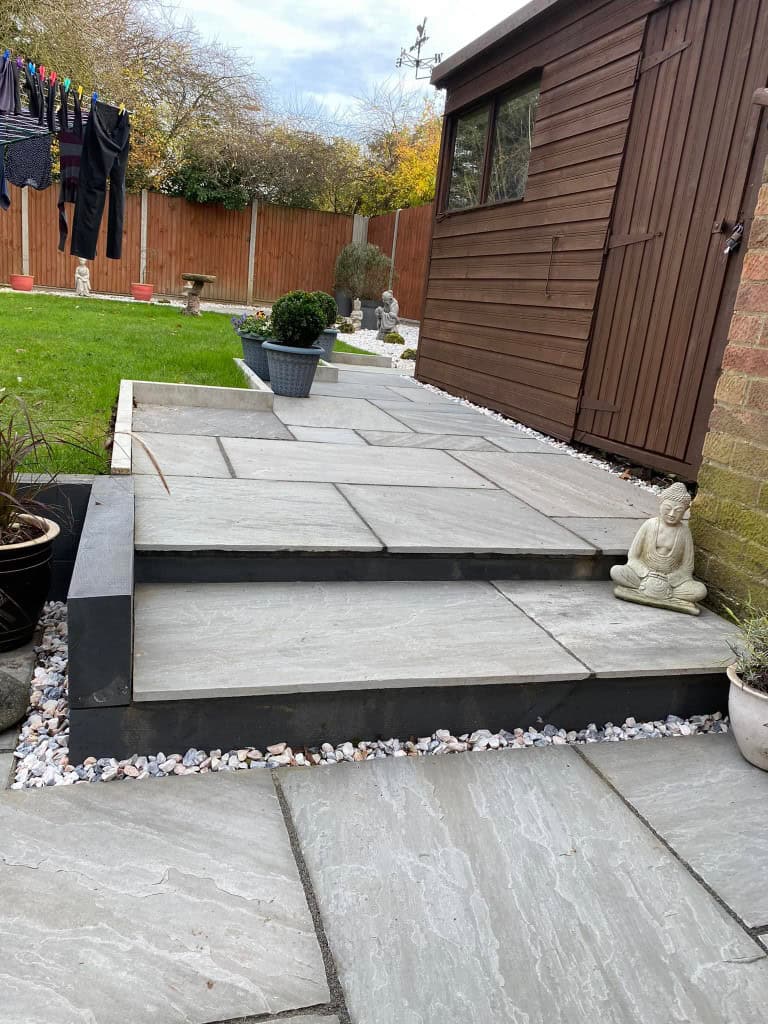 Modern garden patio with steps, potted plants, and garden ornaments.
