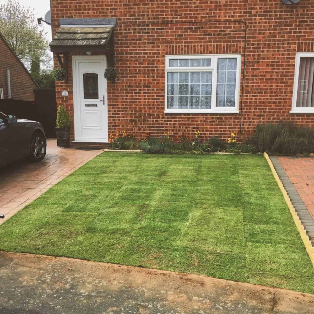 Well-maintained green lawn in front of a brick house in Suffolk.