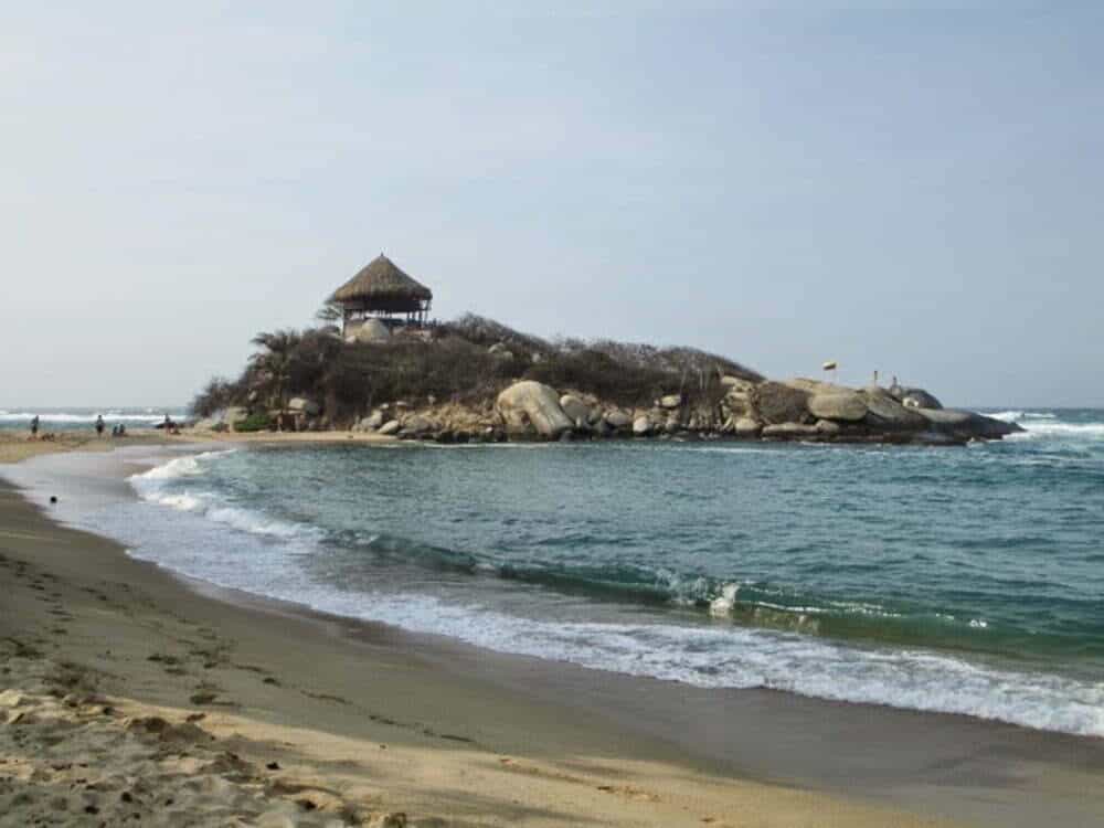 A beach hut on top of a mound of rocks overlooking the ocean