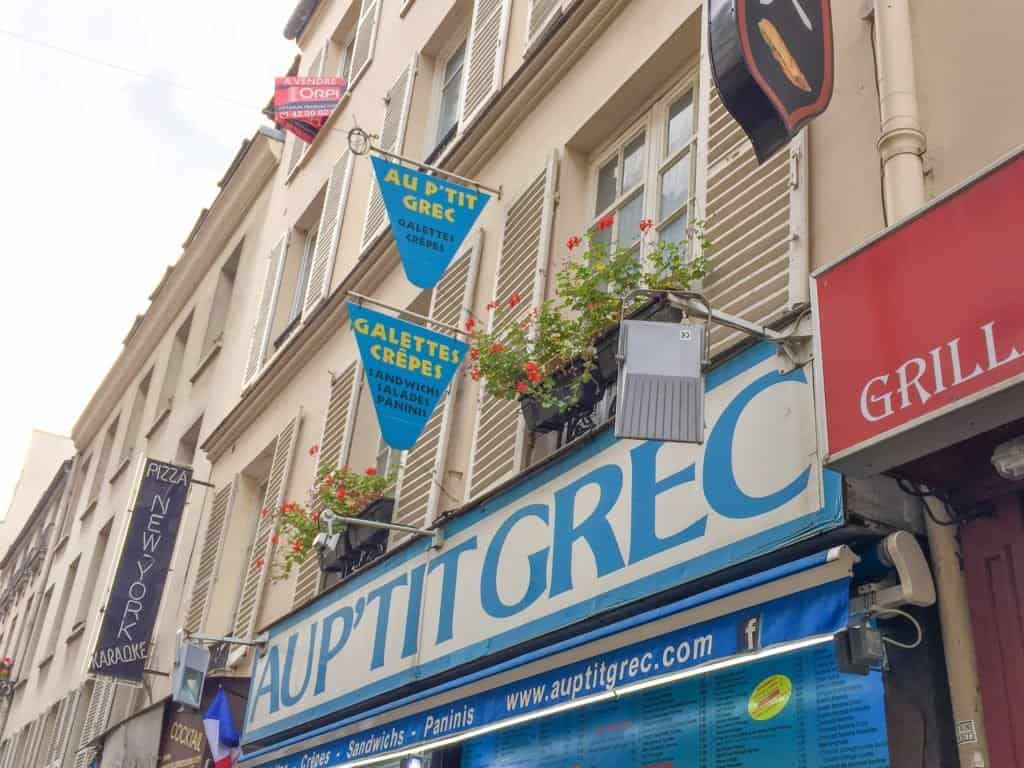 A blue and white shop sign reading Au P'tit Grec