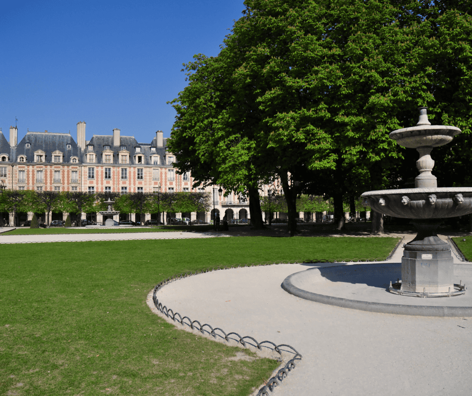 A fountain in the middle of the green grass of Place des Vosges. Apartment buildings are in the background.
