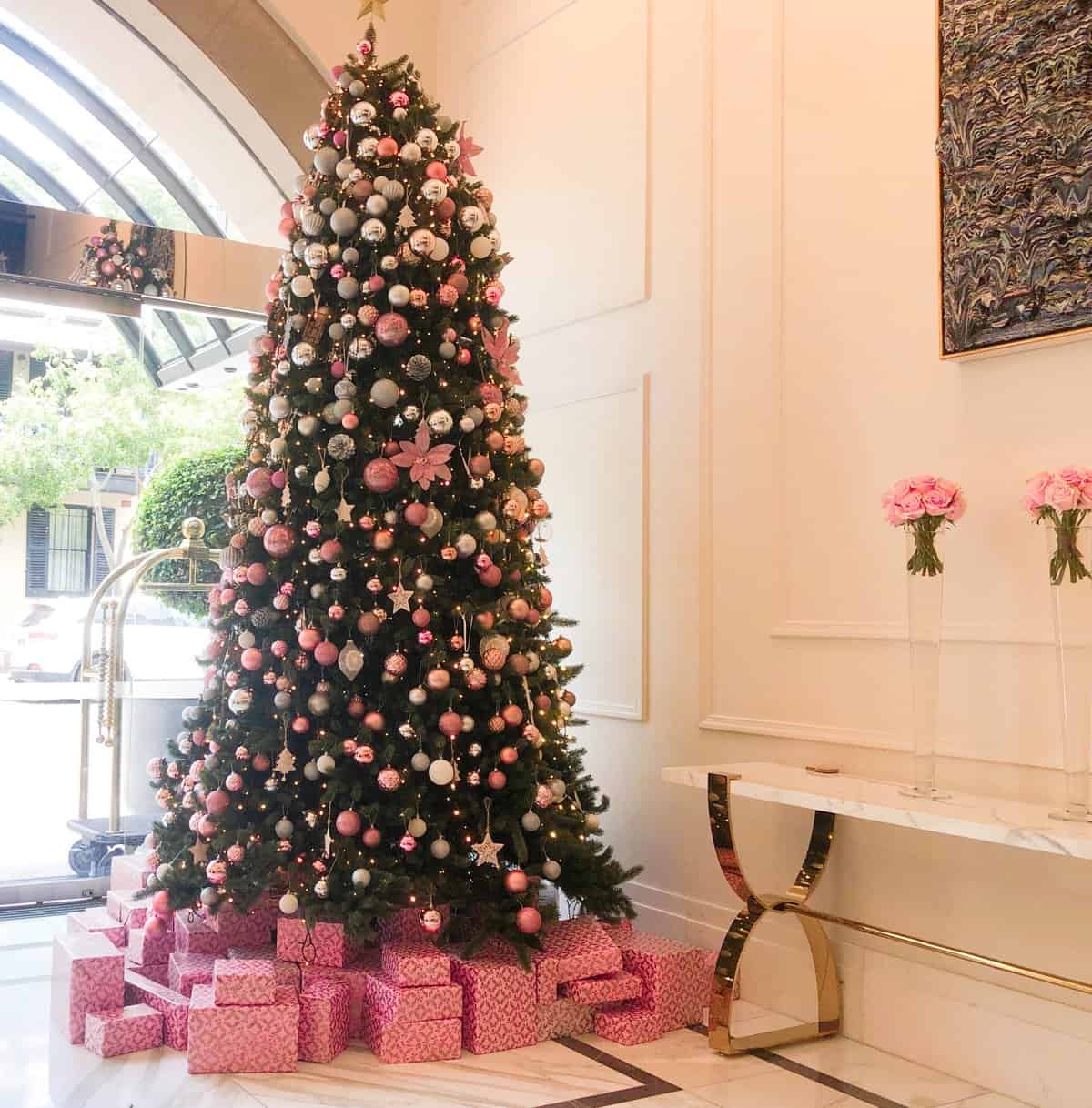 A tall Christmas Tree in the Langham foyer. It is decorated with pink baubles and presents wrapped in pink paper