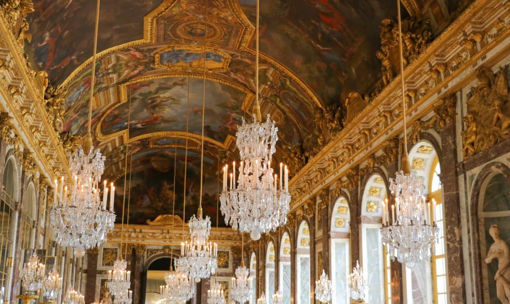 Chandeliers hang from the fresco-covered ceiling in the Hall of Mirrors
