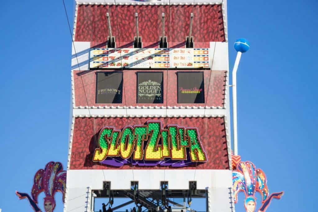 A zipline tower with a green and yellow sign saying "Slotzilla" on the front.