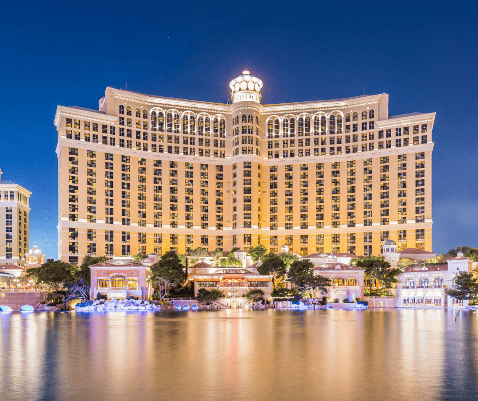 The Bellagio hotel complex is lit up in the twilight with the large lagoon in front of the hotel reflecting the lights.