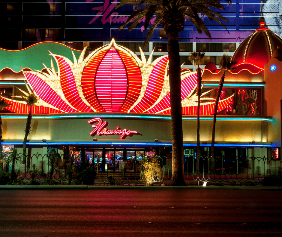 A pink neon sign saying Flamingo with pink and red petal shaped lights above the casino name.