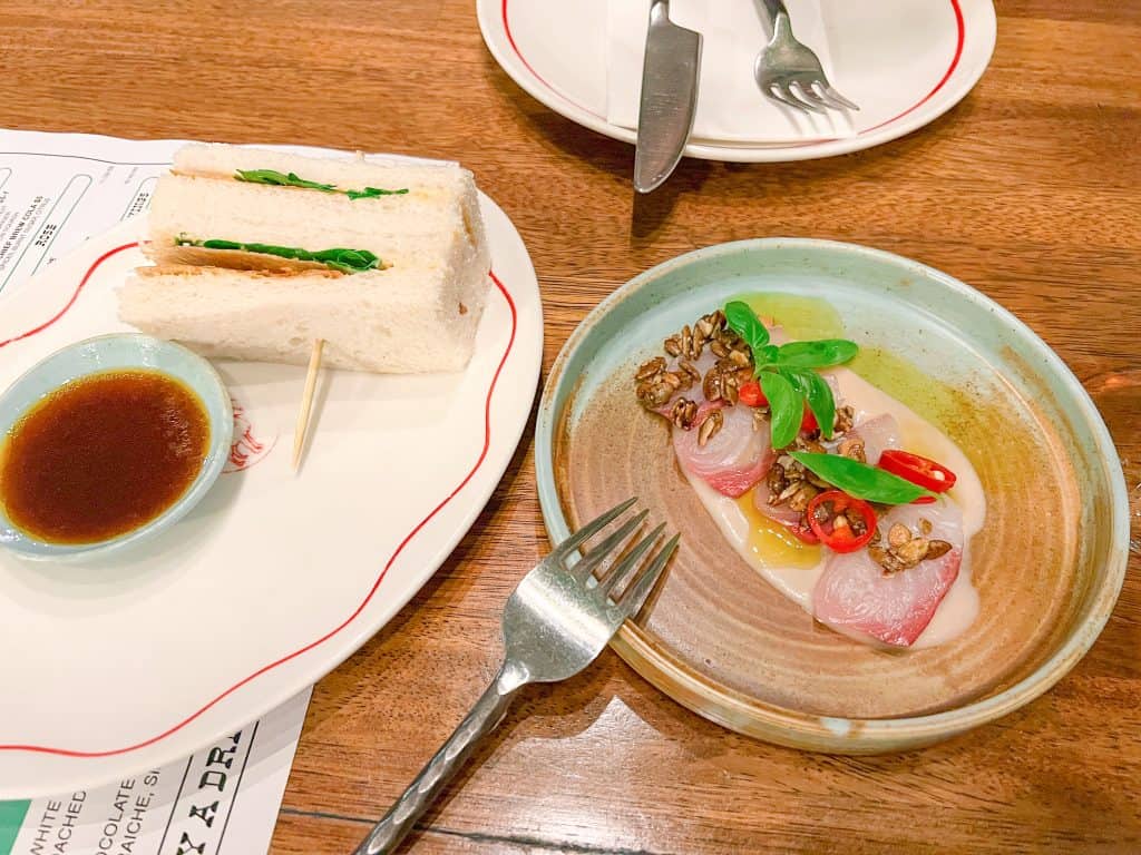 Crispy Chicken Sandwich and Kingfish Sashimi dishes on the table