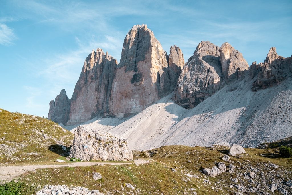 Majestic mountain peaks towering over green and rocky terrain in the Dolomites, Italy, perfect for outdoor adventure and nature photography.