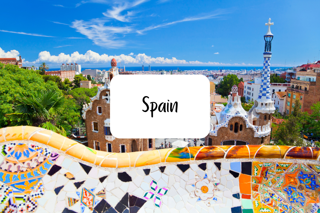 Vibrant view of Park Güell in Barcelona, Spain, showcasing colorful mosaic tiles, unique architectural design by Antoni Gaudí, lush green surroundings, and scenic cityscape under a bright blue sky.