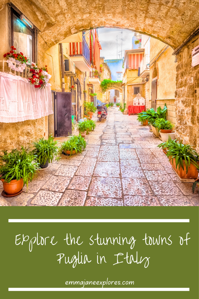 Winding alleyway in Puglia with rustic stone buildings, colourful balconies, potted plants, and cobblestone street, perfect for exploring Italy's charming towns.