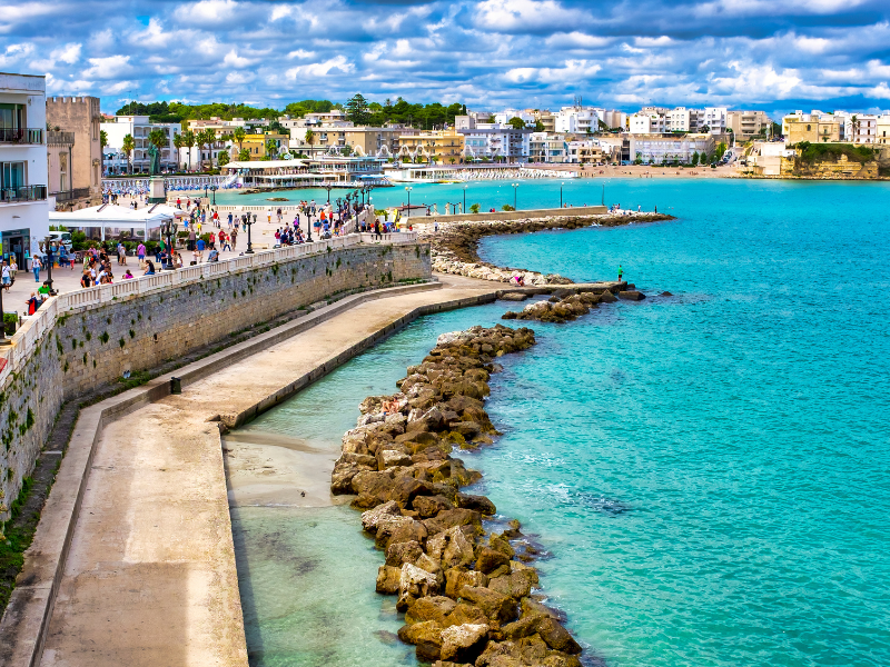 Brighton Beach with colorful buildings, a bustling promenade, and turquoise waters on a lively day in Melbourne, Australia. Perfect for seaside strolls and enjoying coastal scenery.