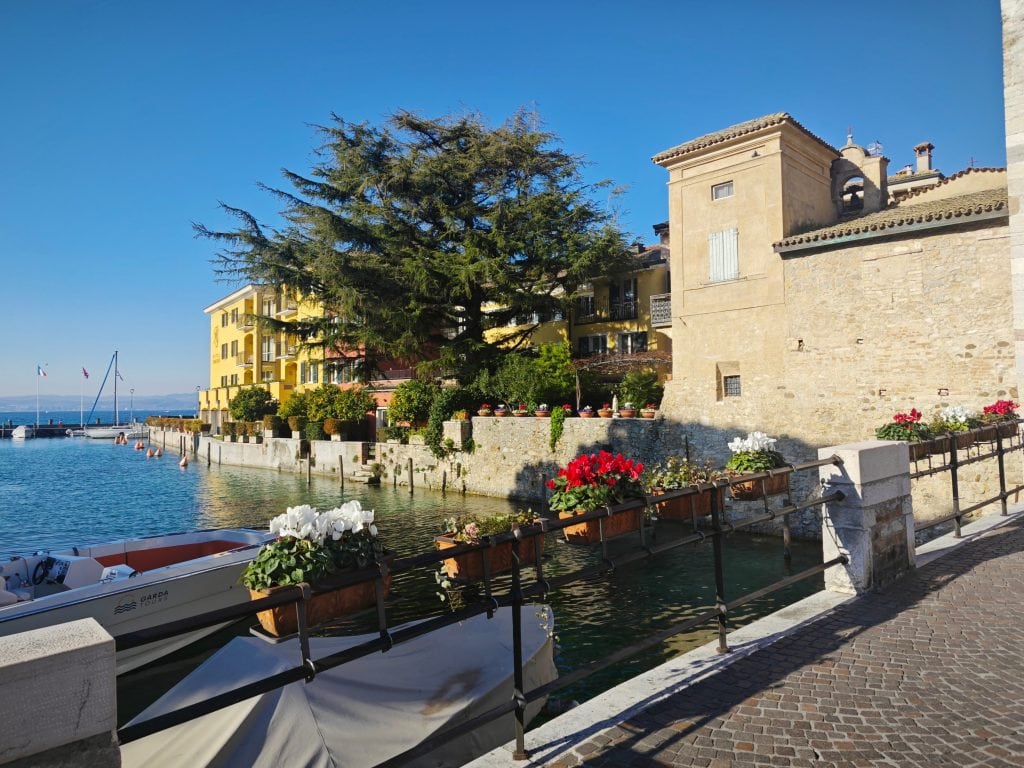 Colourful lakeside village with historic buildings, vibrant flowers, and boats docked along the water, perfect for travel adventures and scenic coastal exploration in Italy.
