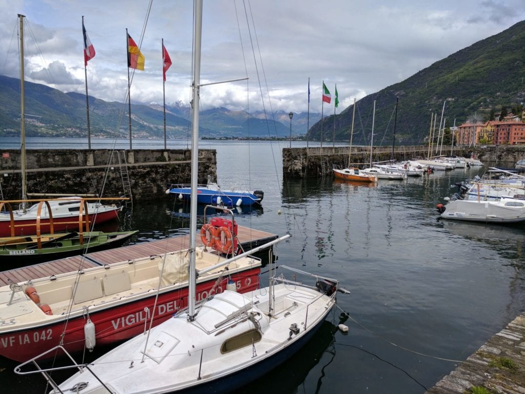 Colourful sailboats docked in a picturesque harbour surrounded by green mountains in Lake Como, Italy. Perfect for sailing, boating adventures, and exploring scenic lakeside villages.
