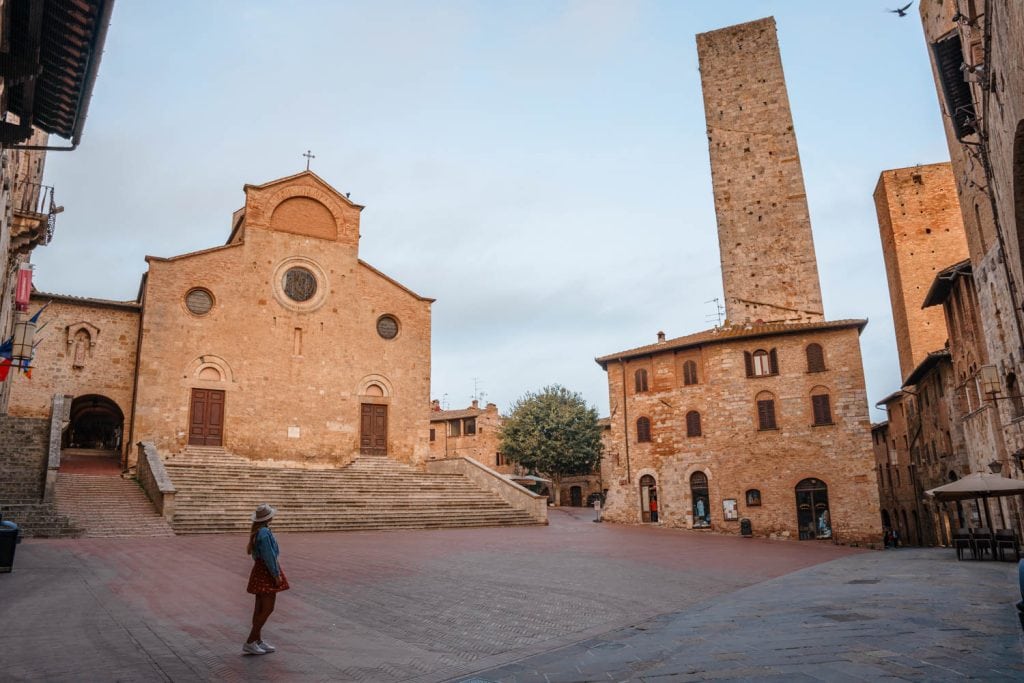 Historic stone church in Tuscany with steps leading to the main entrance, surrounded by old buildings, capturing the charm of Italian architecture.