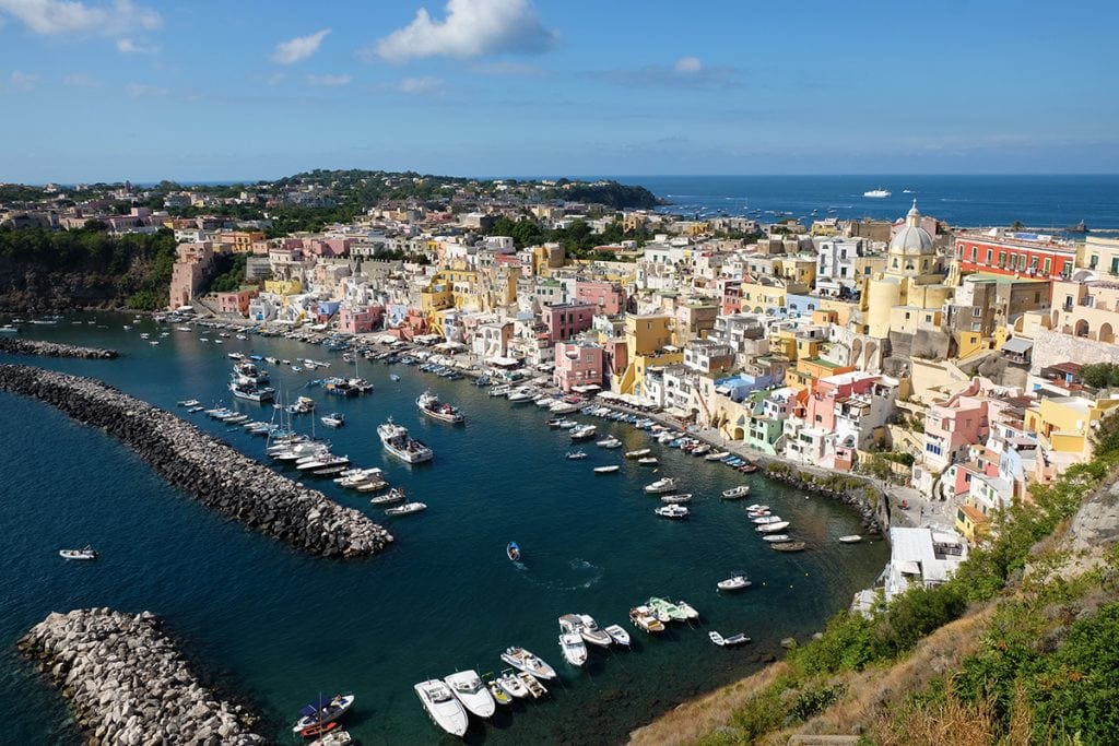 Colourful Mediterranean coastal town with pastel buildings and marina in Sicily, Italy, showcasing vibrant architecture, boats, and stunning seaside views.