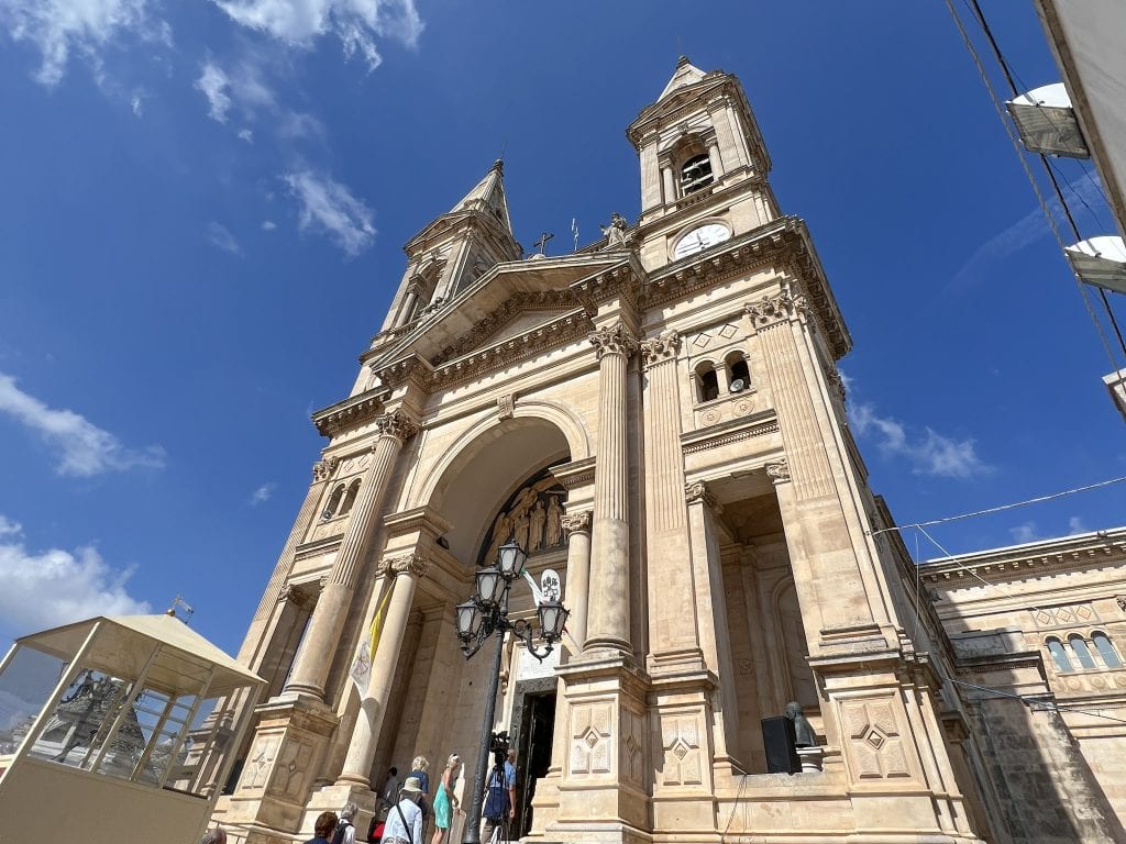 Majestic historic church with grand architecture and tall bell towers under a clear blue sky in Malta.