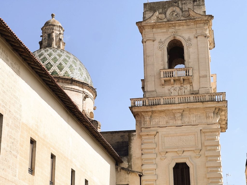 Historical architecture of Italian city, featuring a stone bell tower and decorative dome, with a clear blue sky in the background. Perfect for travel and heritage exploration.