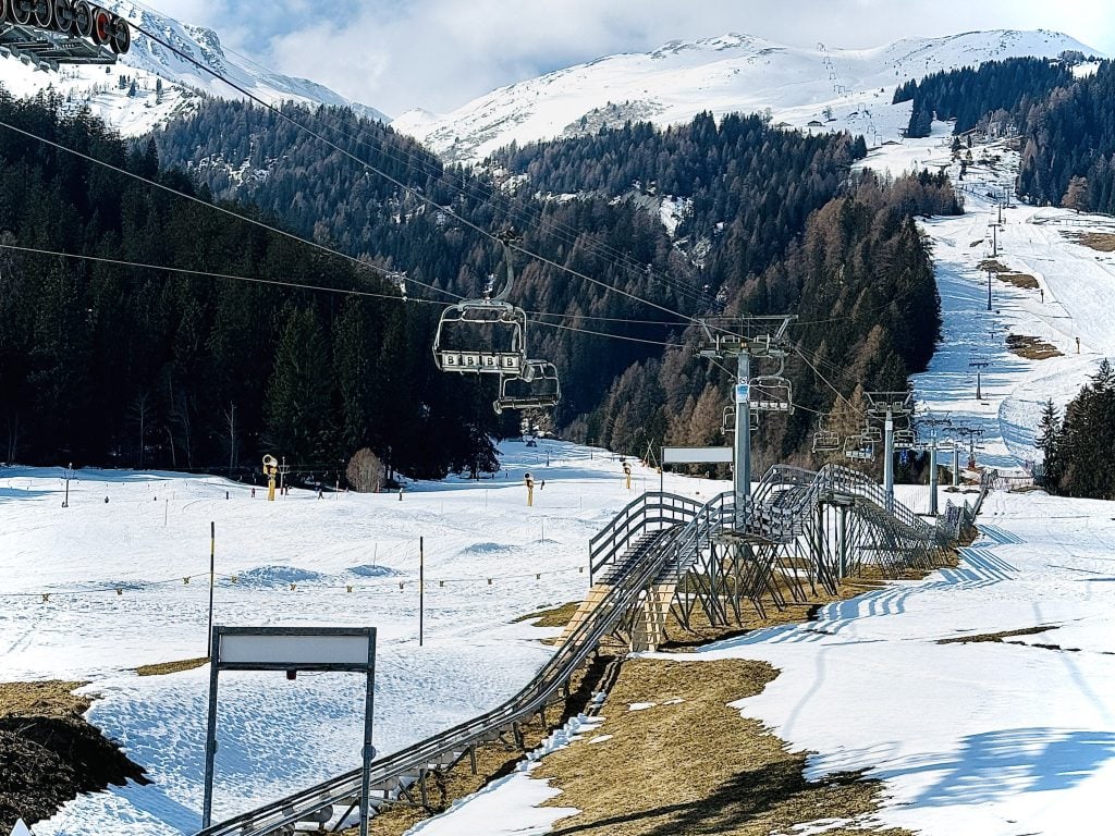 Snow-covered ski slopes with chairlifts in a mountain landscape in Australia, surrounded by pine trees and snow-capped peaks, ideal for winter sports and outdoor adventures.