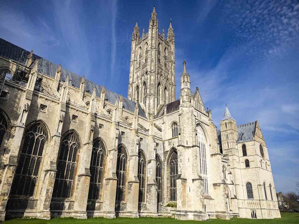 Ely Cathedral's stunning Gothic architecture with soaring towers and intricate stonework, set against a bright blue sky during a clear day.