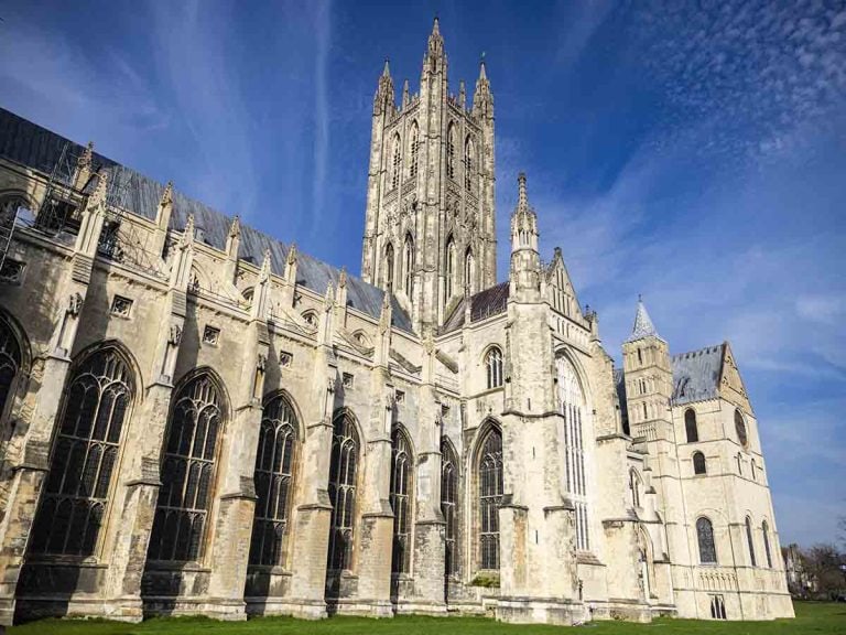 Ely Cathedral's stunning Gothic architecture with soaring towers and intricate stonework, set against a bright blue sky during a clear day.