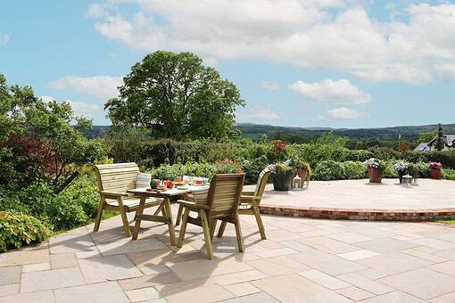 Sunny outdoor patio with wooden dining table and chairs, surrounded by lush greenery and vibrant potted flowers, perfect for garden entertaining and relaxing in a beautiful landscape.