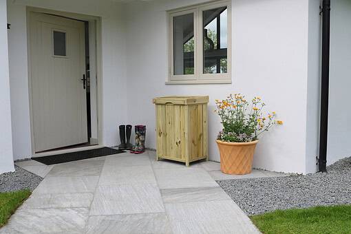 Bright outdoor porch entrance with white walls, wooden storage box, potted flowers, and rain boots, showcasing stylish home and garden decor from Empire Home and Garden.