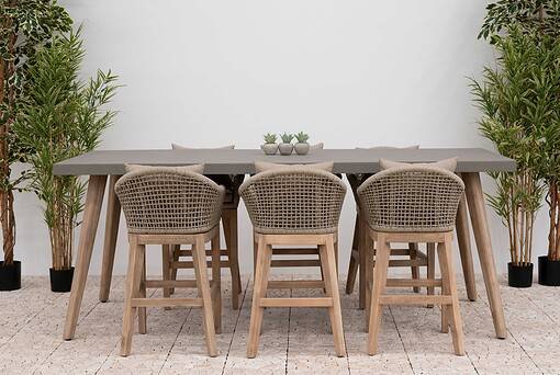 Modern outdoor dining table with wicker chairs, lush potted plants, and neutral decor, perfect for patio or garden entertaining. Stylish and durable furniture from Empire Home and Garden.