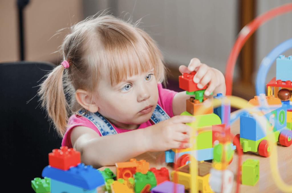A girl is sitting on the floor playing with building blocks.