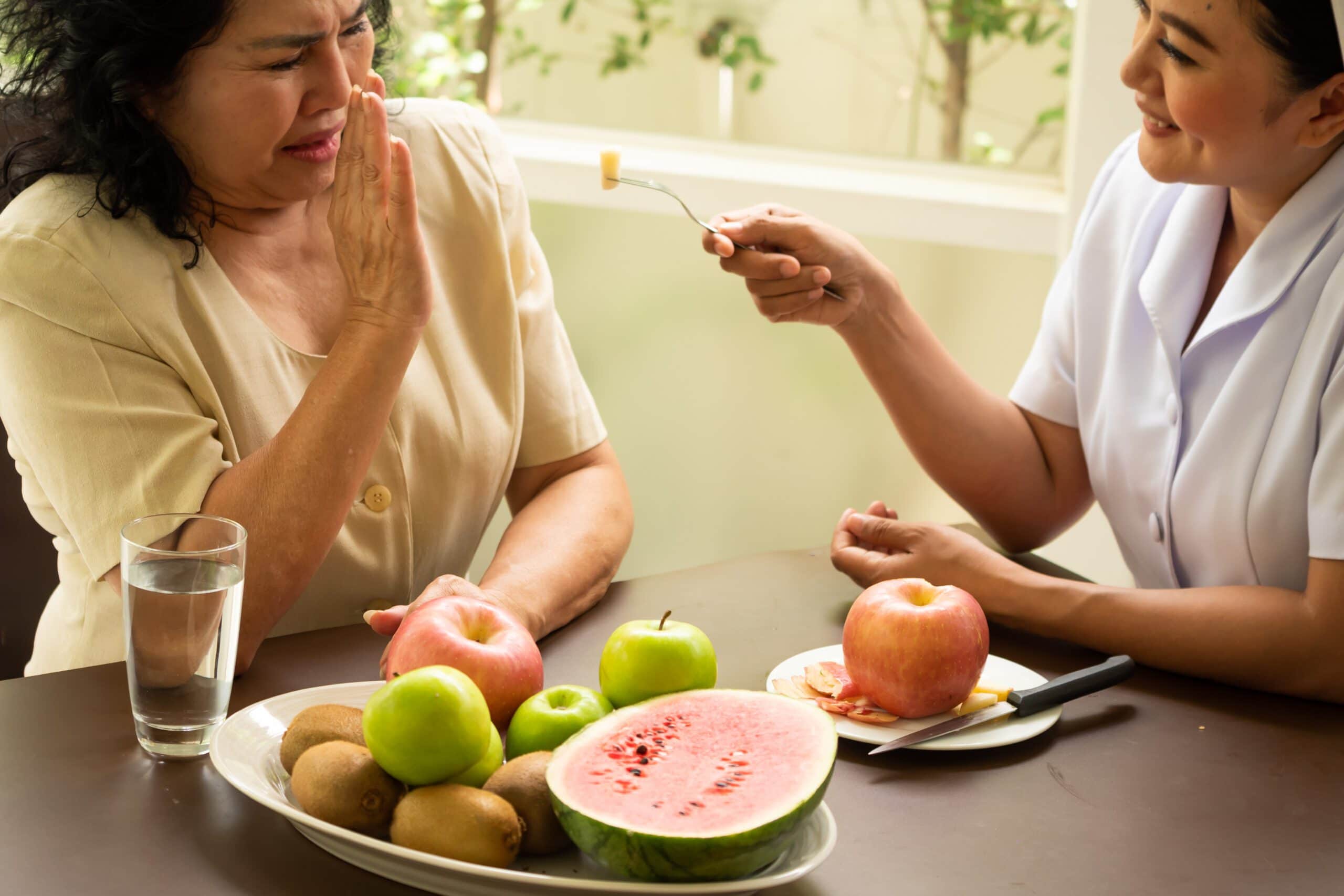 Adult female patient refusing apple from nurse.