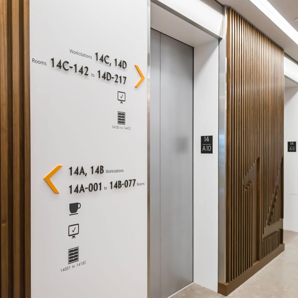 Deloitte elevator lobby featuring dimensional wayfinding directional signage and millwork integrated with wayfinding level indictor (colour-coded with a white wall).