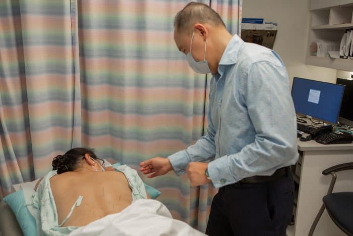 a practitioner administers acupuncture to a patient.
