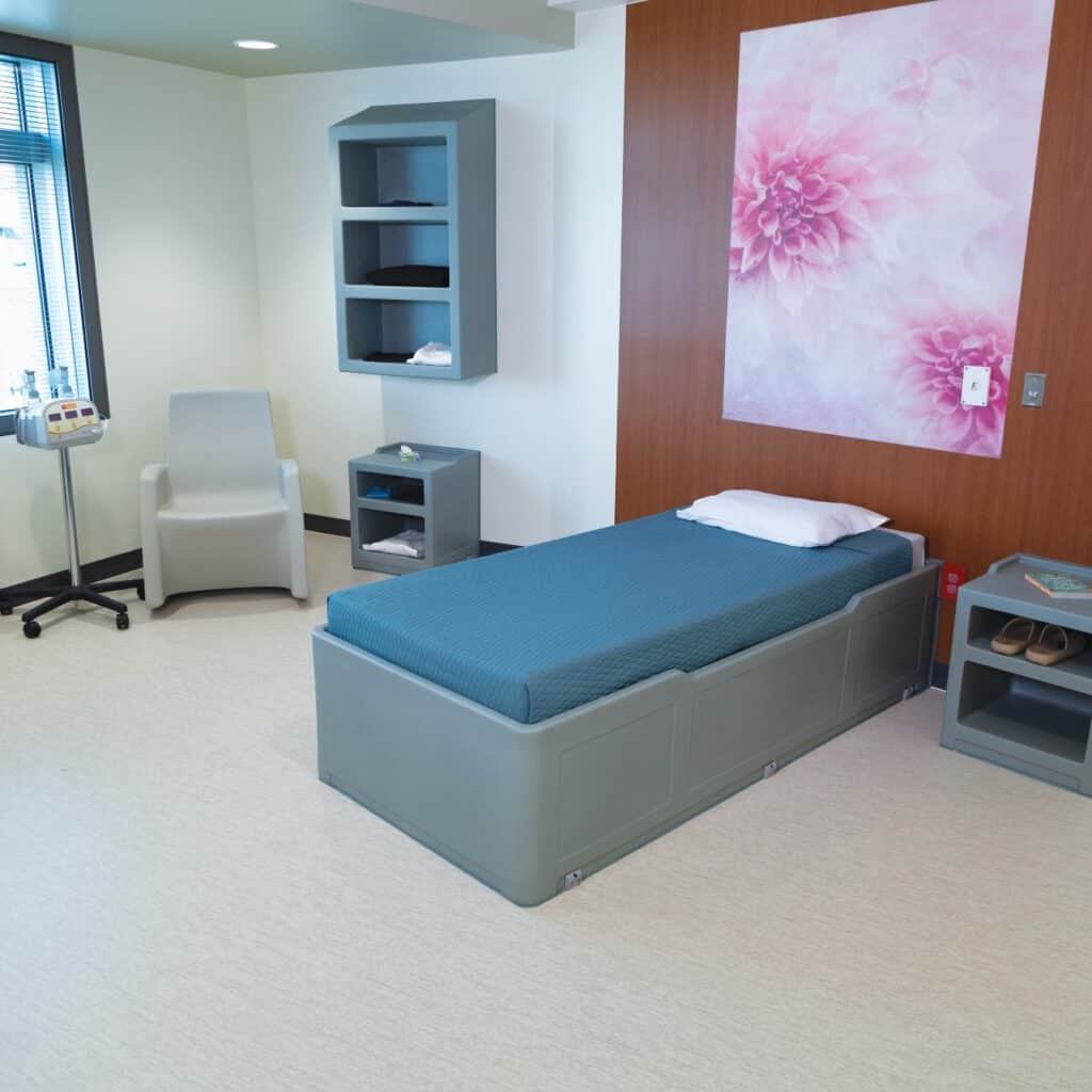 A room on the perinatal mental health unit featuring a bed, nightstand, and rocking chair.