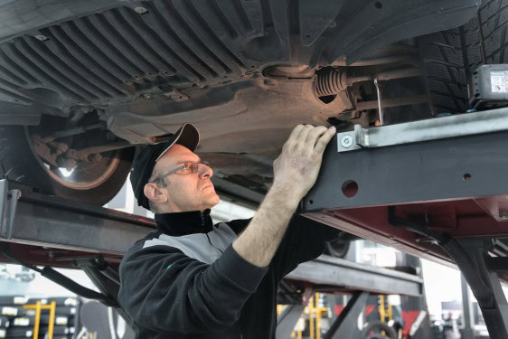 Skilled technician applying OEM-grade paint to a vehicle underside for perfect match.