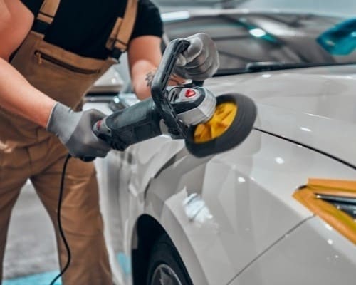 Technician repairing car dent with polishing tool at European Autoworks.