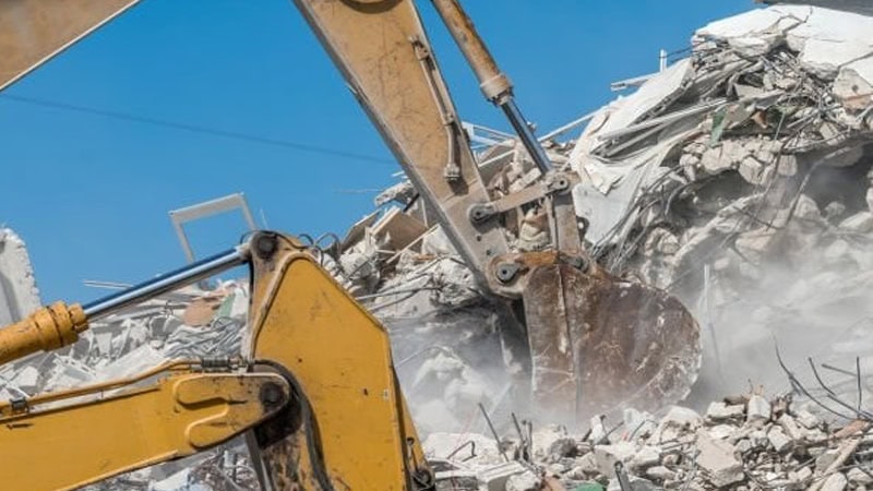 Excavator arm demolishing a house