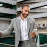 Business professional in a suit using a smartphone outdoors.