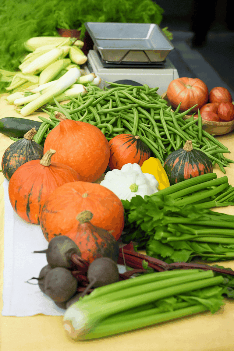 Fresh regional vegetables on a market stall in Graz: pumpkins, green beans, celery, turnips and tomatoes on a table covered in yellow, with old market scales in the background.