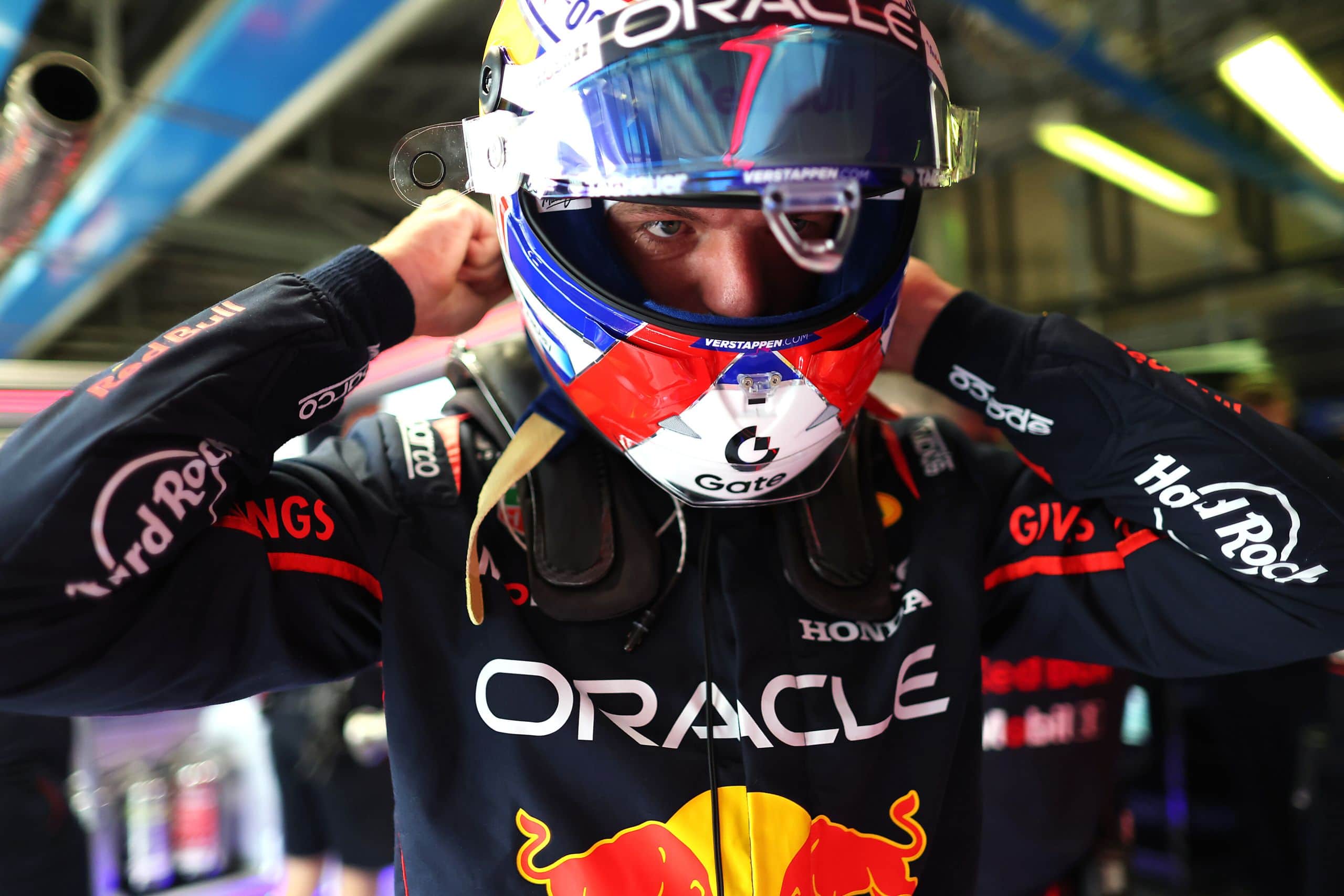 F1 driver preparing in garage for race or practice session.