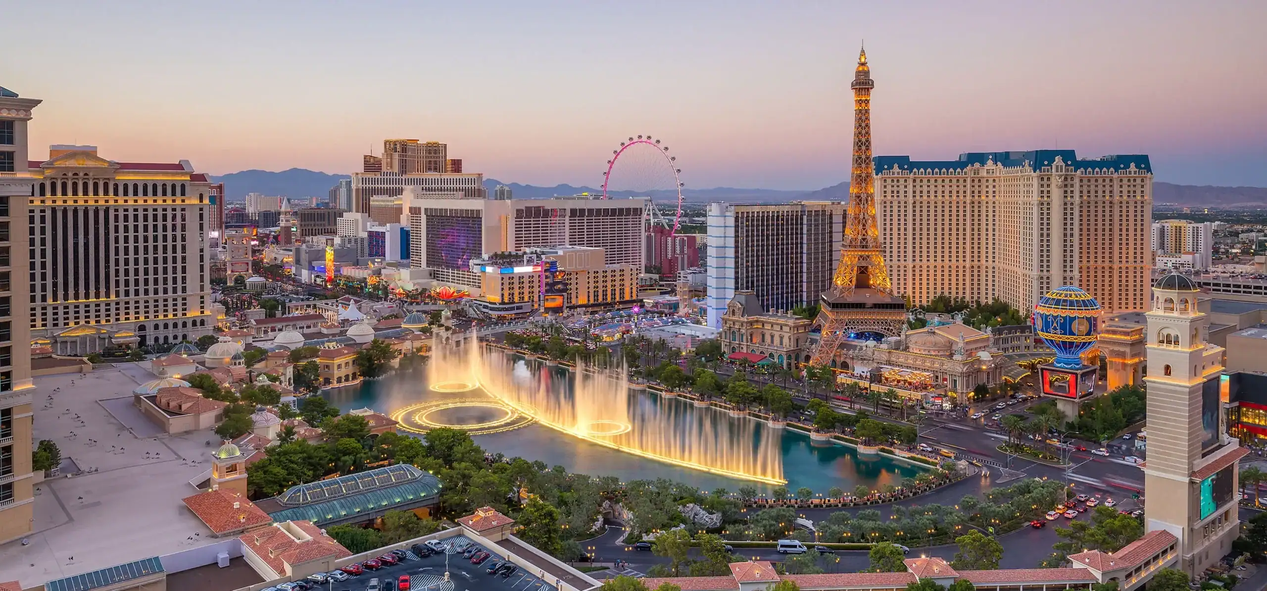 Las Vegas skyline featuring the Eiffel Tower replica and Bellagio Fountains at sunset. Iconic Las Ve.