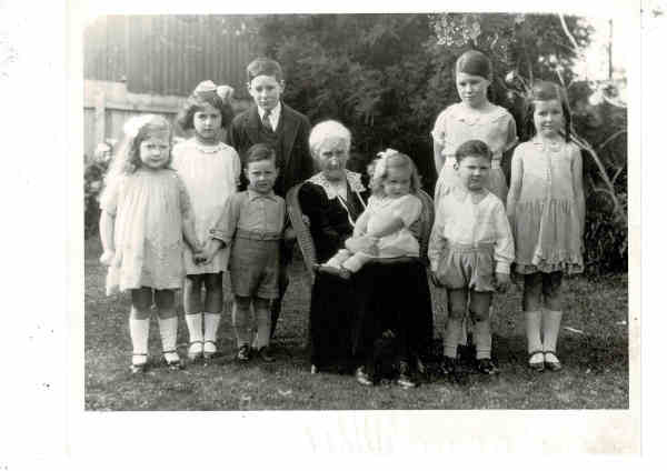 Family group photo outdoors, including children and elderly woman, in a backyard setting.