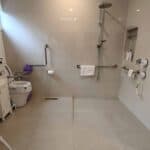 Accessible bathroom with grab bars and shower seat for mobility assistance.