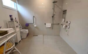 Accessible bathroom with grab bars and shower seat for mobility assistance.