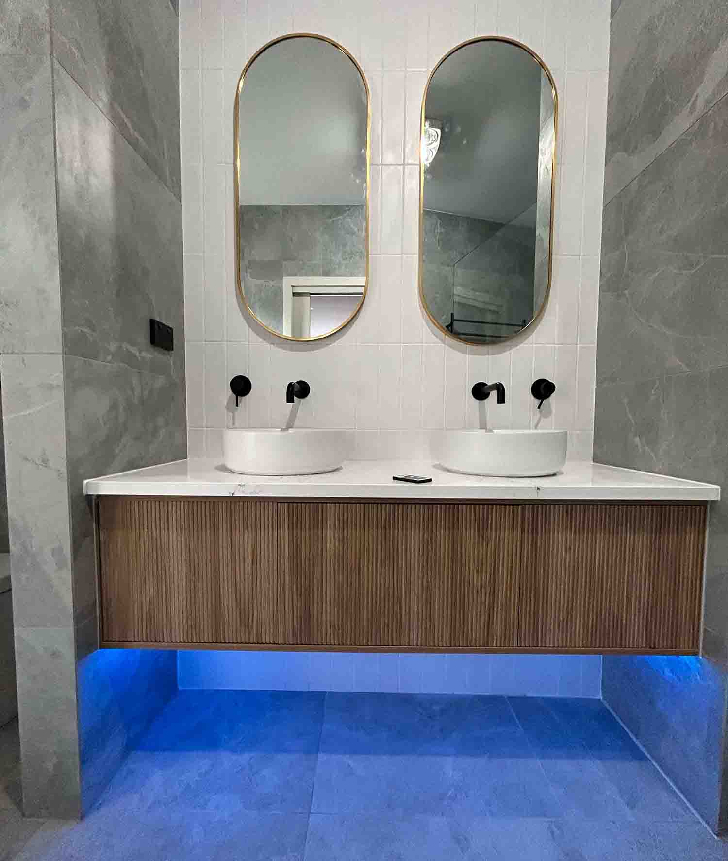 Bathroom vanity with dual sinks, oval mirrors, and modern decor.