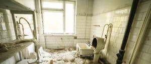 Old bathroom with broken shower and damaged tiles for repair.